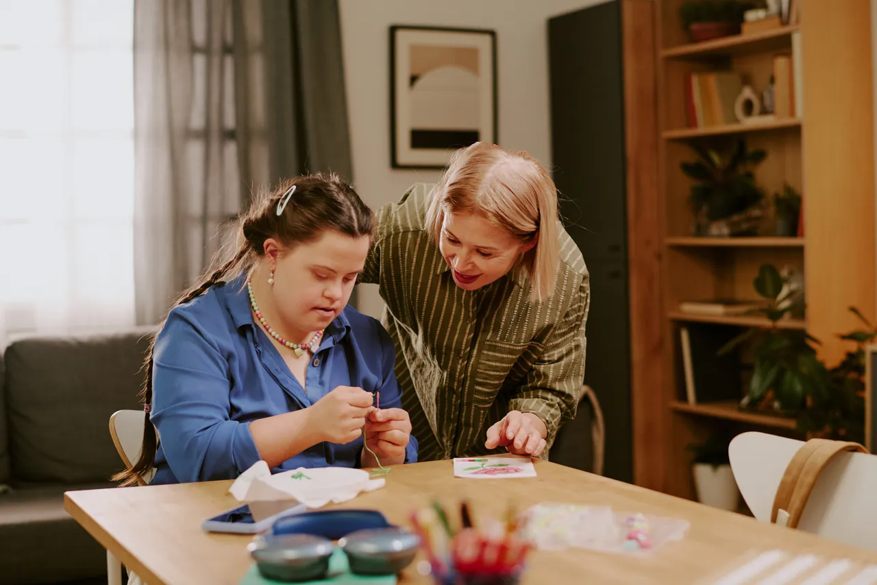 Two women working together on an embroidery activity at home